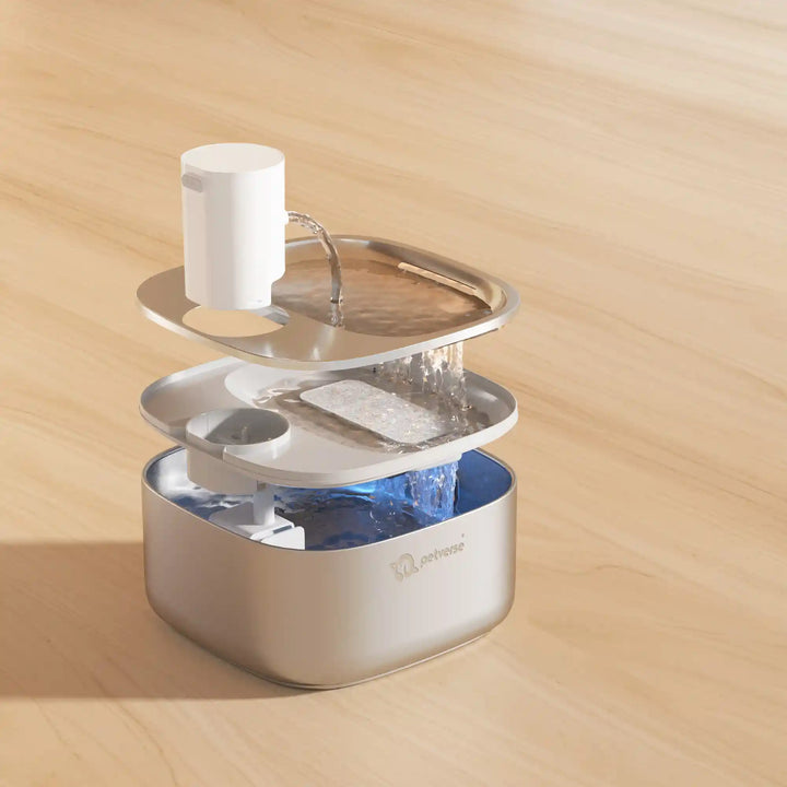 Pet water fountain showing top spout pouring water into layered filtration and base reservoir.