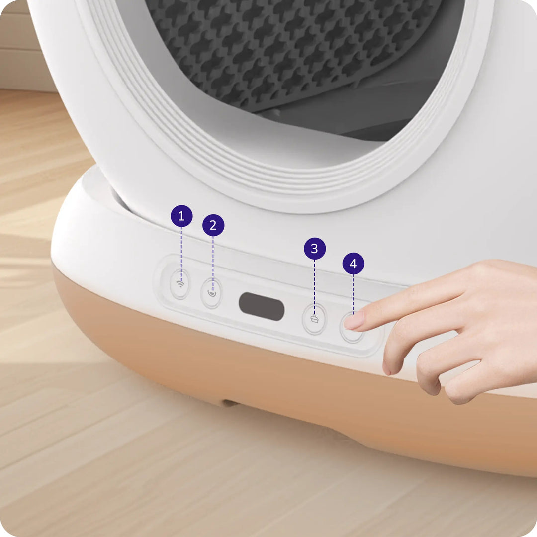 Close‑up of litter box control panel with four labeled buttons and a hand pressing one.